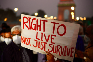 A hand holds up a protest sign that reads "Right to Live Not Just Some."