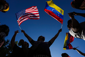 A person waving miniature US and Venezuelan flags in each hand.