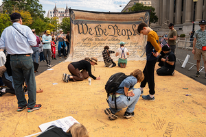 People signing a large banner of the US Constitution at the No Kings protest in Washington