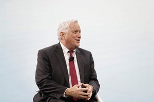 Walter Isaacson speaking in red tie, in front of light grey background