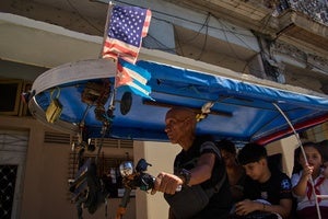A driver steers his bicycle taxi decorated with US and Cuban flags in Havana, Cuba