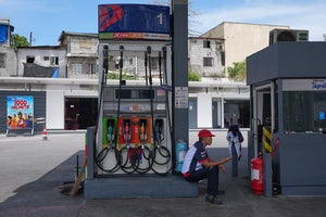 A worker gestures to indicate "no gas" at a gasoline station in the Philippines