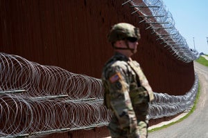 a guard stands in front of the US-Mexico border wall