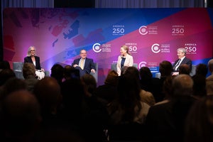 Four people sitting on a stage in front of an audience
