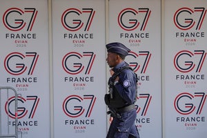 A French police officer walks past G7 logos in Evian-les-Bains