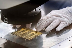 A factory working lining up a data chip under a machine.