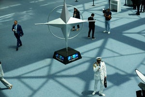 Participants walk near displays during the NATO Defense Industry Forum