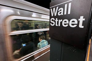 A sign reading "Wall Street" hangs in the New York subway.