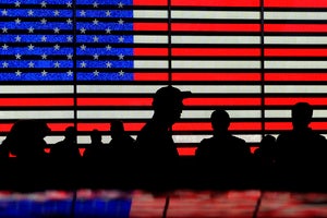 Silhouettes against a backdrop of the American flag