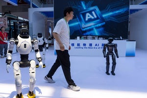 A person passes by a display of robots and a sign that says AI