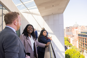 Members of the Emerging Leaders Class of 2026 stand on a balcony and look out onto Washington, DC, during the annual cohort trip in May 2026.
