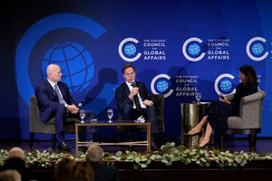 Three people sit in chairs while speaking into microphones