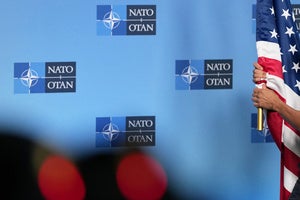 A person carries the US flag onto the podium prior to a media statement from NATO Secretary General Mark Rutte
