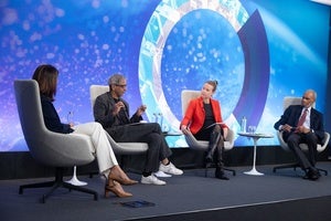 Speakers sitting on stage with a blue backdrop.