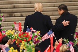 President Donald Trump and Chinese President Xi Jinping walk in front of people waving American and Chinese flags