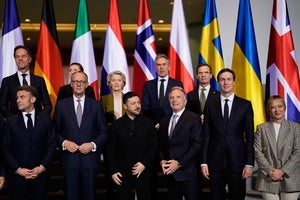 World leaders stand in front of a group of national flags