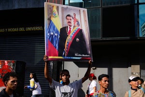 A government supporter holds a banner with a photo of President Nicolas Maduro during a protest demanding his release from U.S. custody in Caracas, Venezuela.