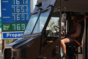 A UPS truck driver stands in transit as gasoline prices are advertised at over seven dollars a gallon at a gas station downtown Los Angeles Tuesday, March 3, 2026.