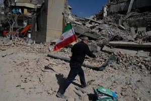  man carries an Iranian flag to place on the rubble of a police facility struck during the U.S.–Israeli military campaign in Tehran, Iran, Wednesday, March 4, 2026. 