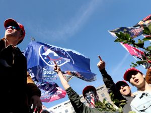 People protest and wave flags saying America First
