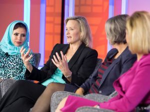 Four women speak while sitting in chairs on-stage