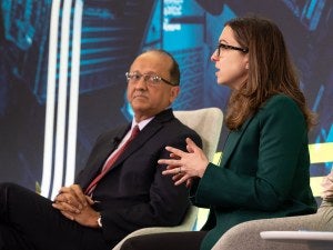 Two people talk while sitting in chairs on-stage
