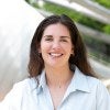 Marina Barbera in a white professional button down shirt is smiling looking into the camera outside at Millennium Park