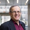 Headshot of Robert Rosner wearing dark red shirt, black jacket, and smiling