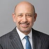 Blankfein headshot wearing dark grey jacket, blue tie, in front of light grey background