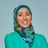 Photo of a woman in a turquoise dress and headscarf crossing her arms