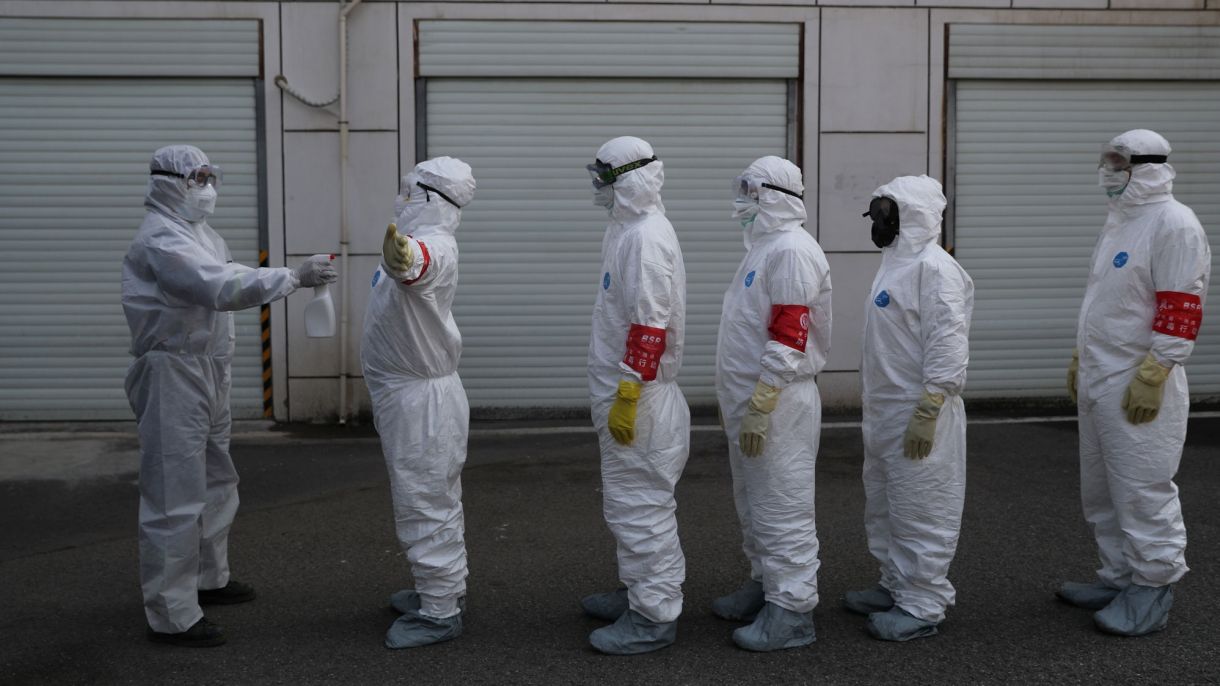 Volunteers in protective suits line up to be disinfected | Chicago Council on Global Affairs