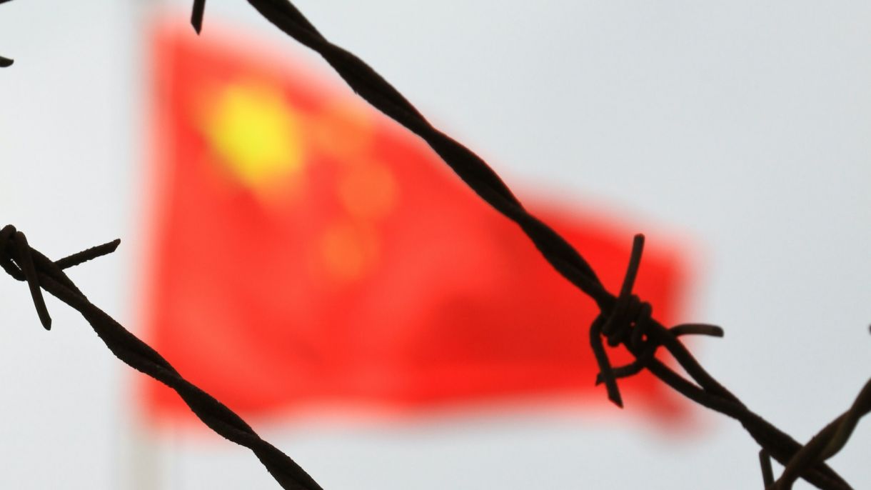The Chinese flag waves behind barbed wire at the border crossing.