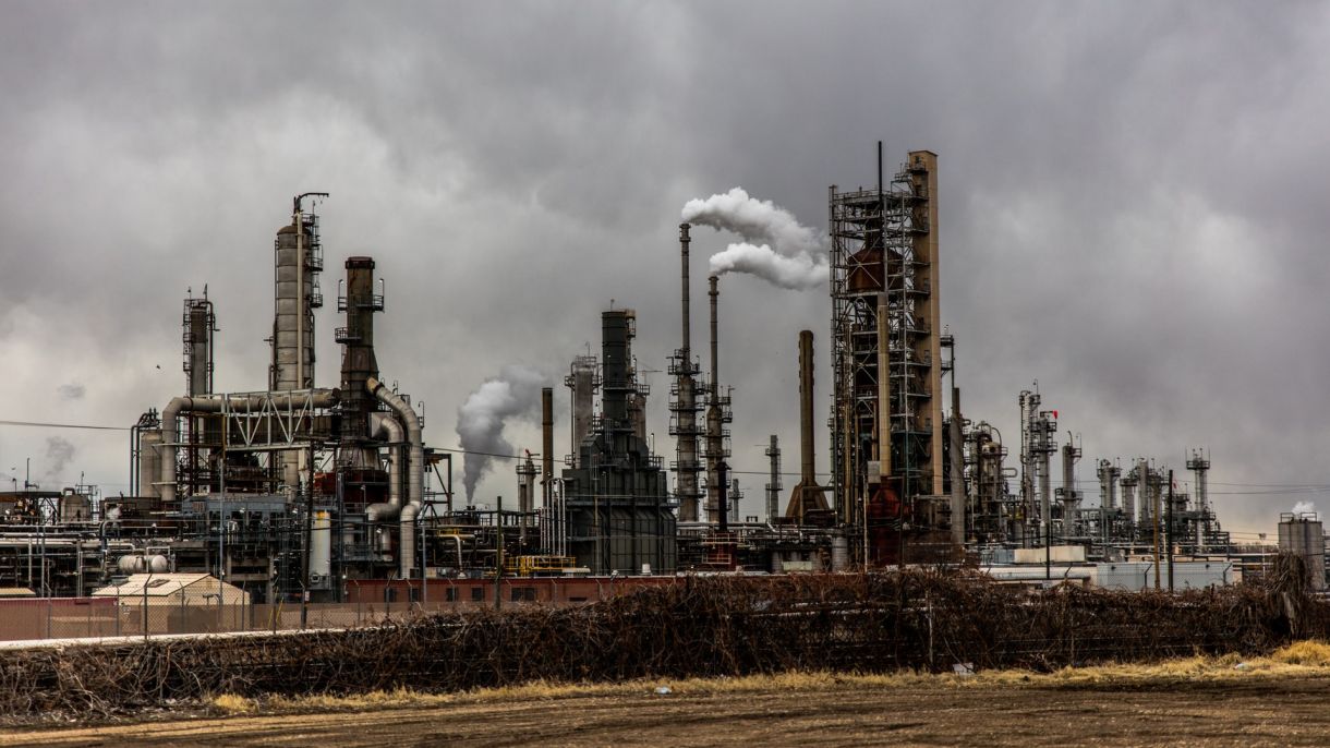 Smoke stacks at a factory release smoke into a gray sky.