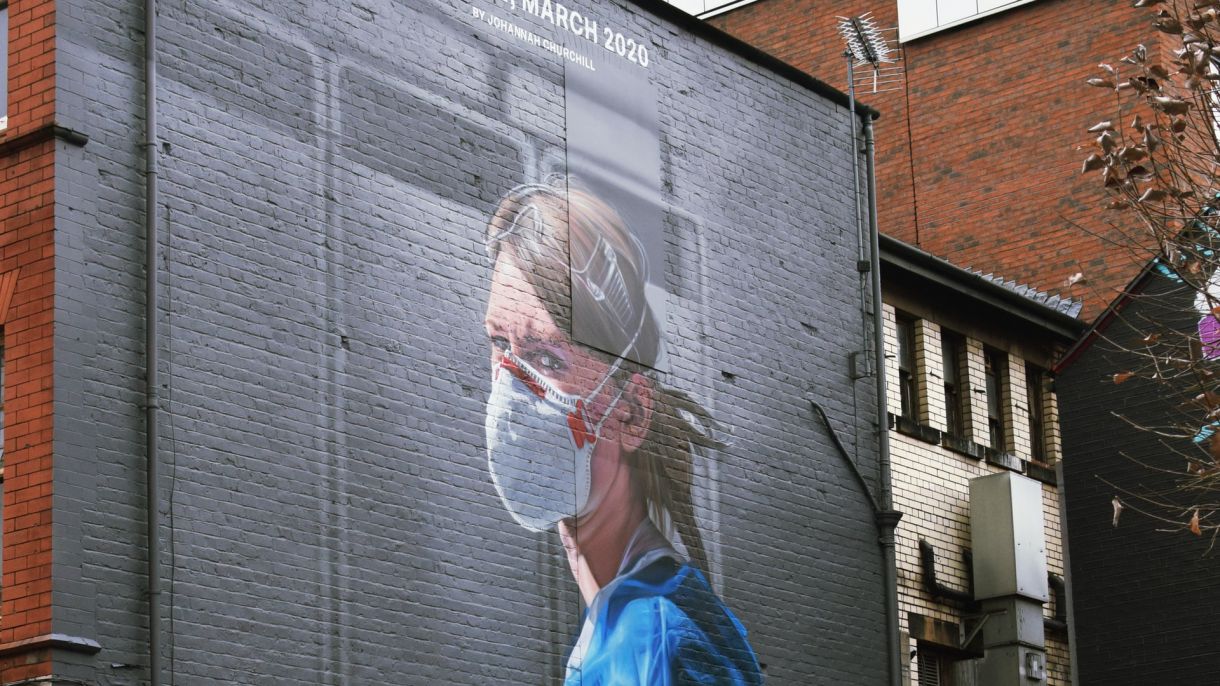A mural on a brick wall of a person wearing medical gear