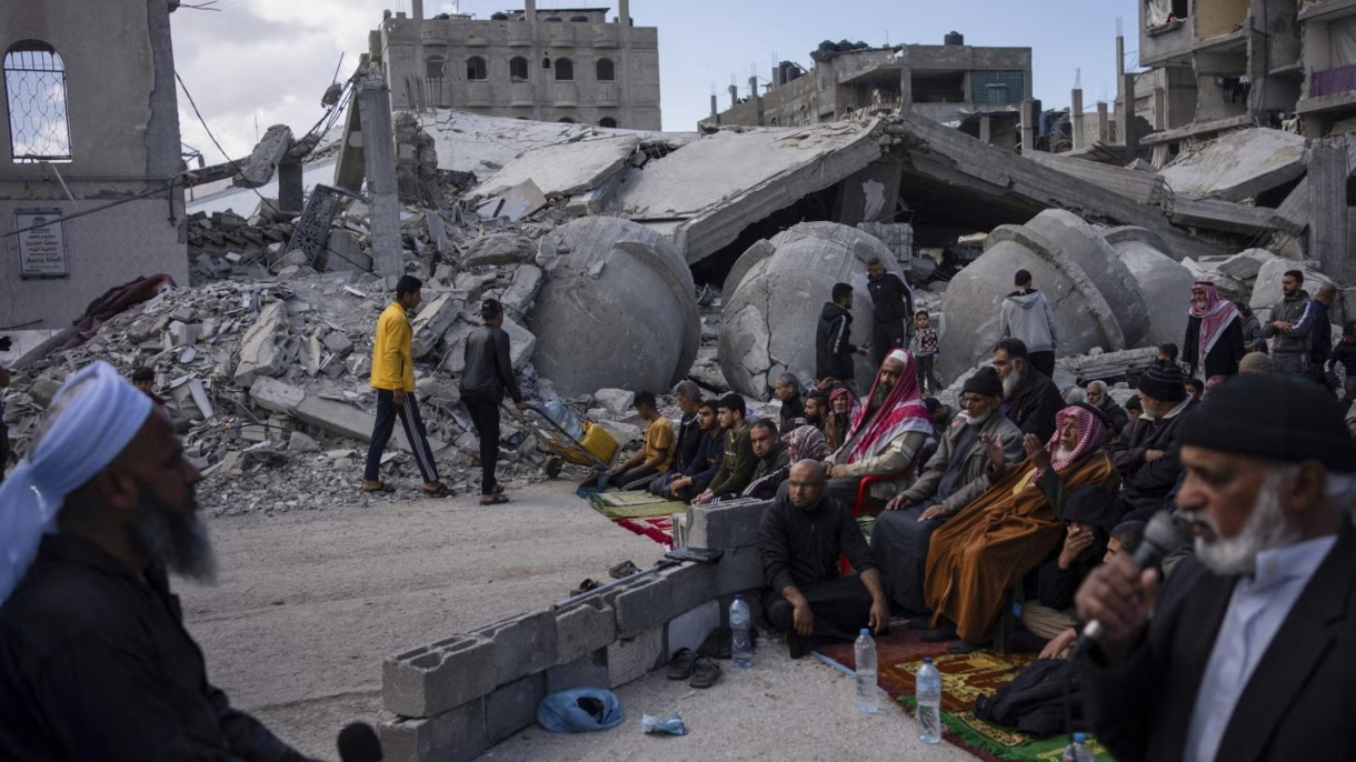 Palestinians pray in front of a mosque destroyed by the Israeli airstrikes in Rafah, Gaza Strip