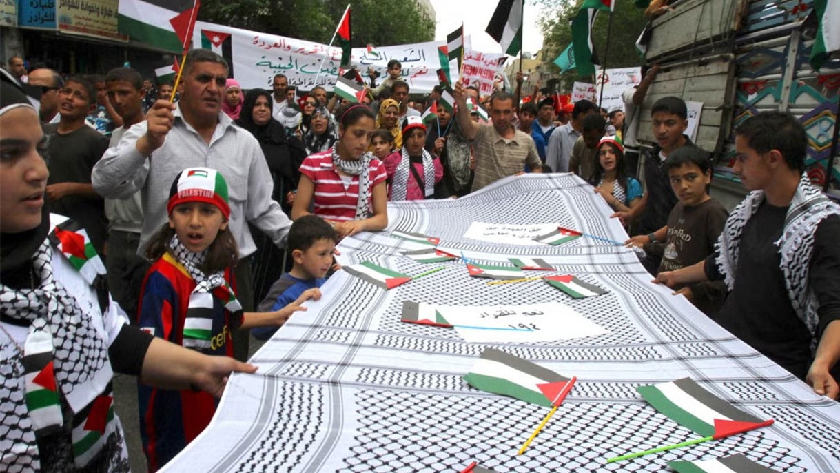 Jordanian children hold a huge kefiyah, a traditional Palestinian scarf.