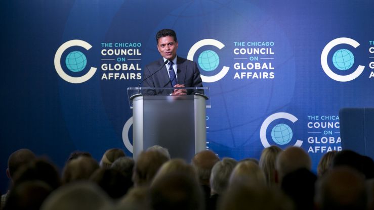 Fareed Zakaria speaking at a podium in front of a blue backdrop with the Council logo on it. 