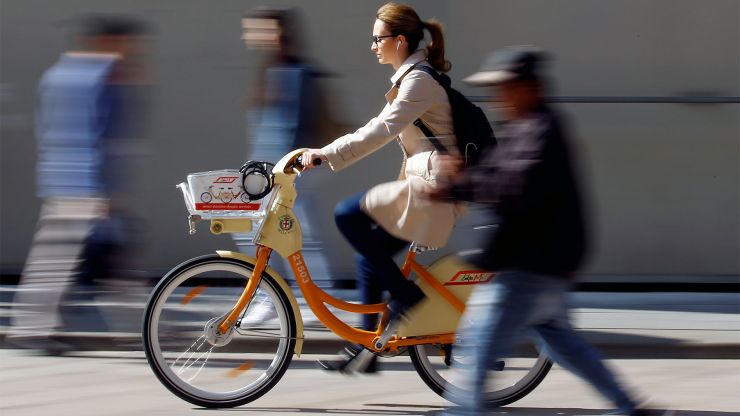 A woman rides a bike on the street in Milan