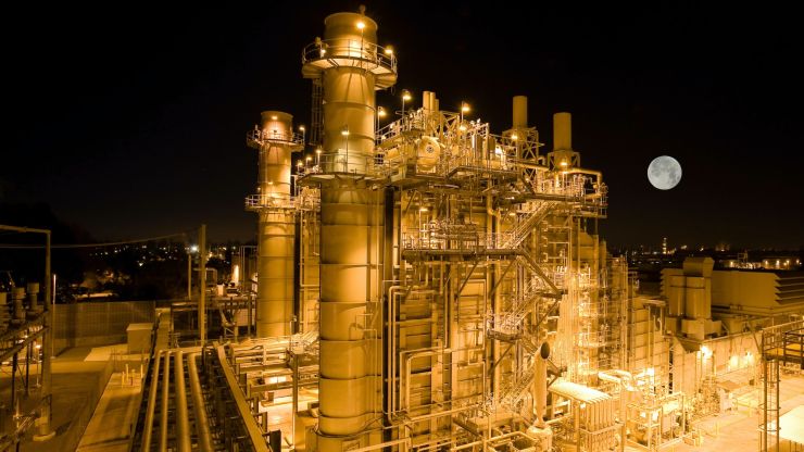 An aerial view of a power plant at night, with the moon in the background