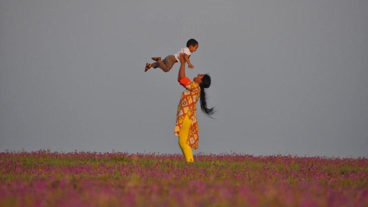 A woman tosses her child in the air.