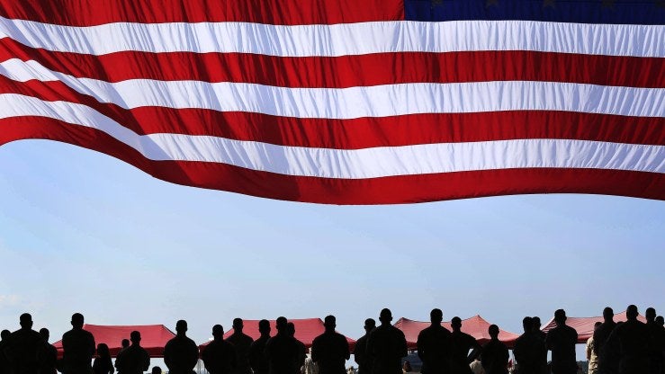 An American flag flies over a row of people