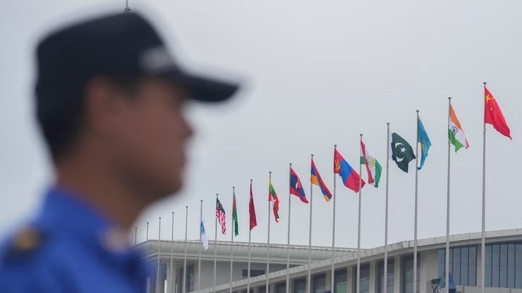 A security guard stands near the flags of Shanghai Cooperation Organization member states outside the venue in Tianjin, China on August 30, 2025.