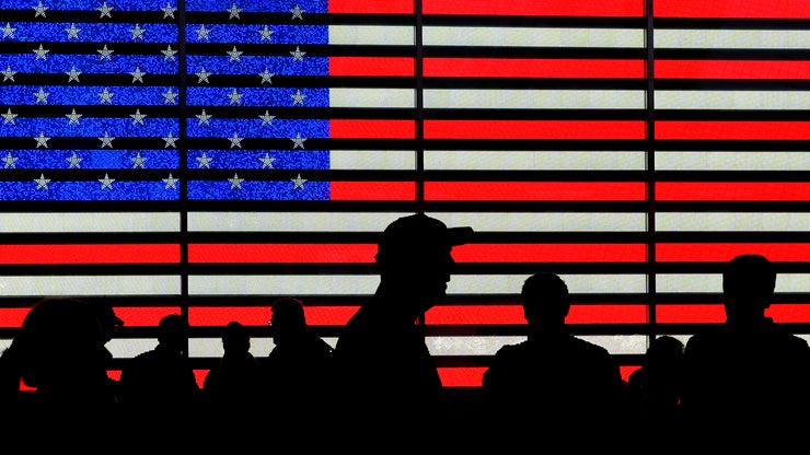 Silhouettes against a backdrop of the American flag
