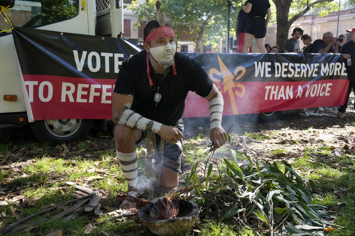 Aboriginal man Josh Sly of the Muggera Dancers prepares a fire for a smoking ceremony at the start of an Invasion Day rally in Sydney, Australia