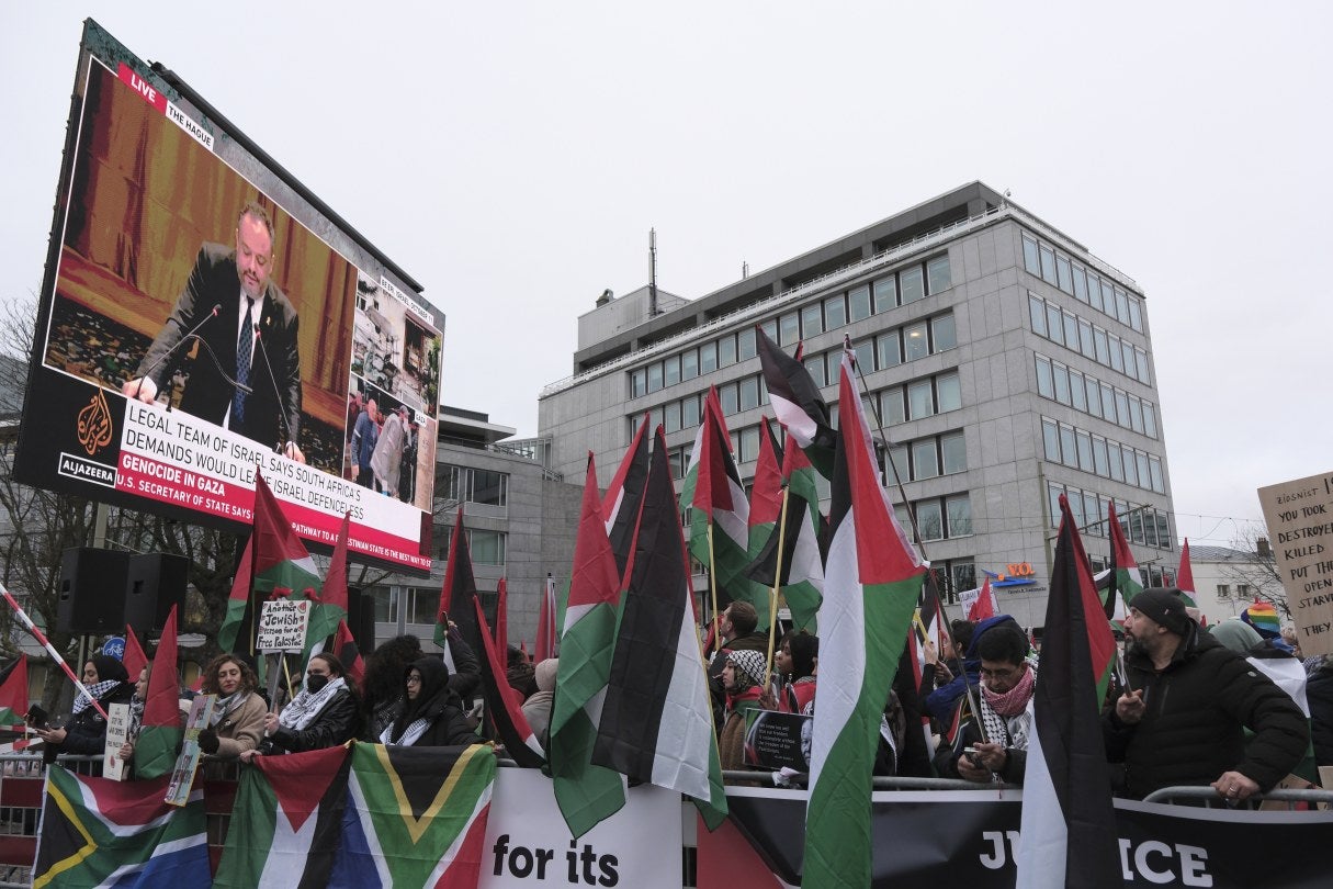  people holding flags in front of a big projector screen