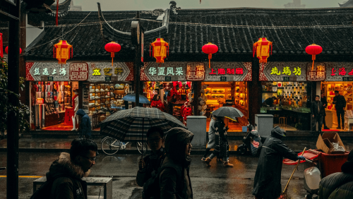 People walk through the rain on a a busy street in China.