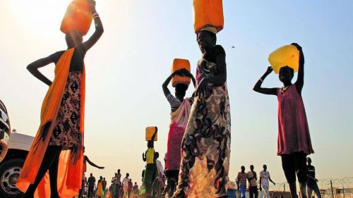 South Sudanese carry water containers on their heads