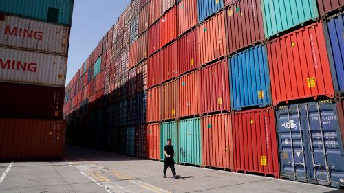 A man walks in front of shipping containers in Shanghai