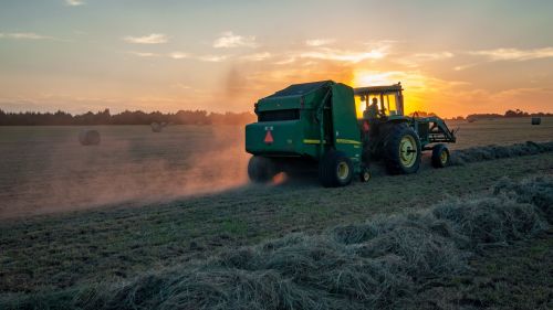 A farmer rides a tractor through a crop while harvesting