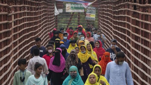 People walk through a fenced-in tunnel wearing colorful clothes